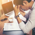 stressed man with laptop holding his head